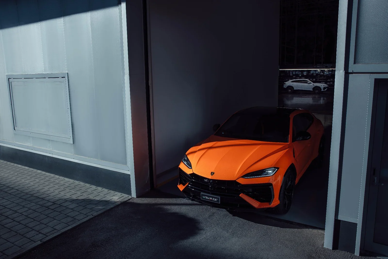 Orange Lamborghini Urus SE front three-quarter view at the factory