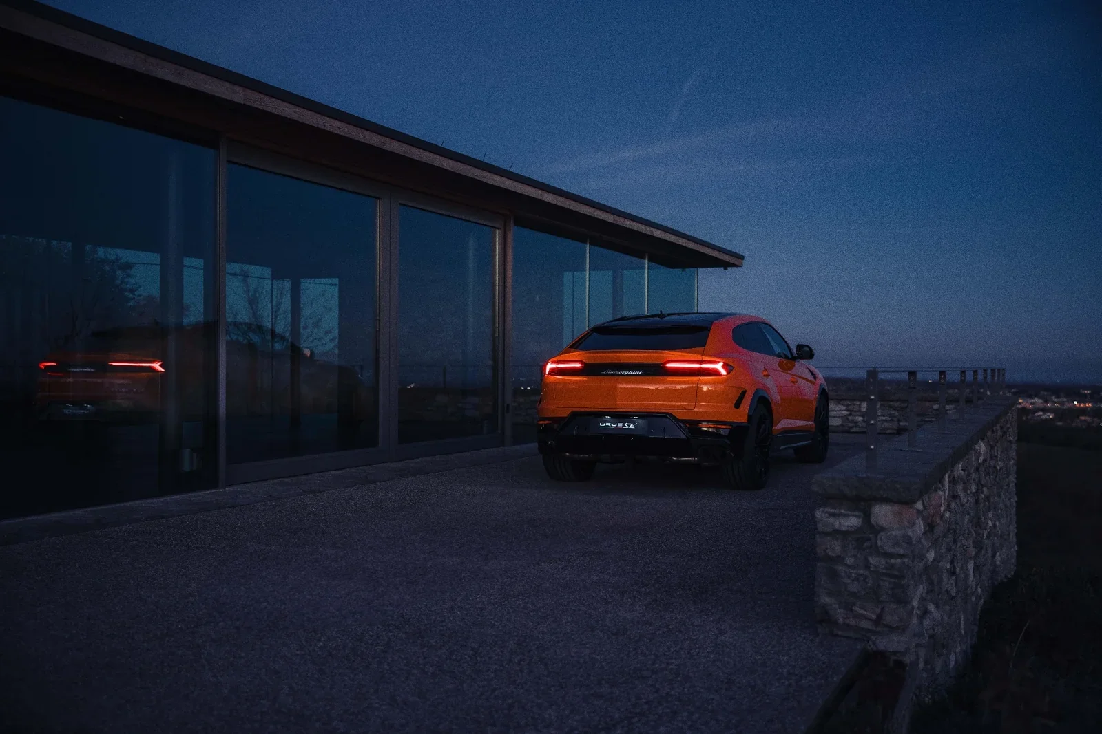 Orange Lamborghini Urus SE rear exterior view at night