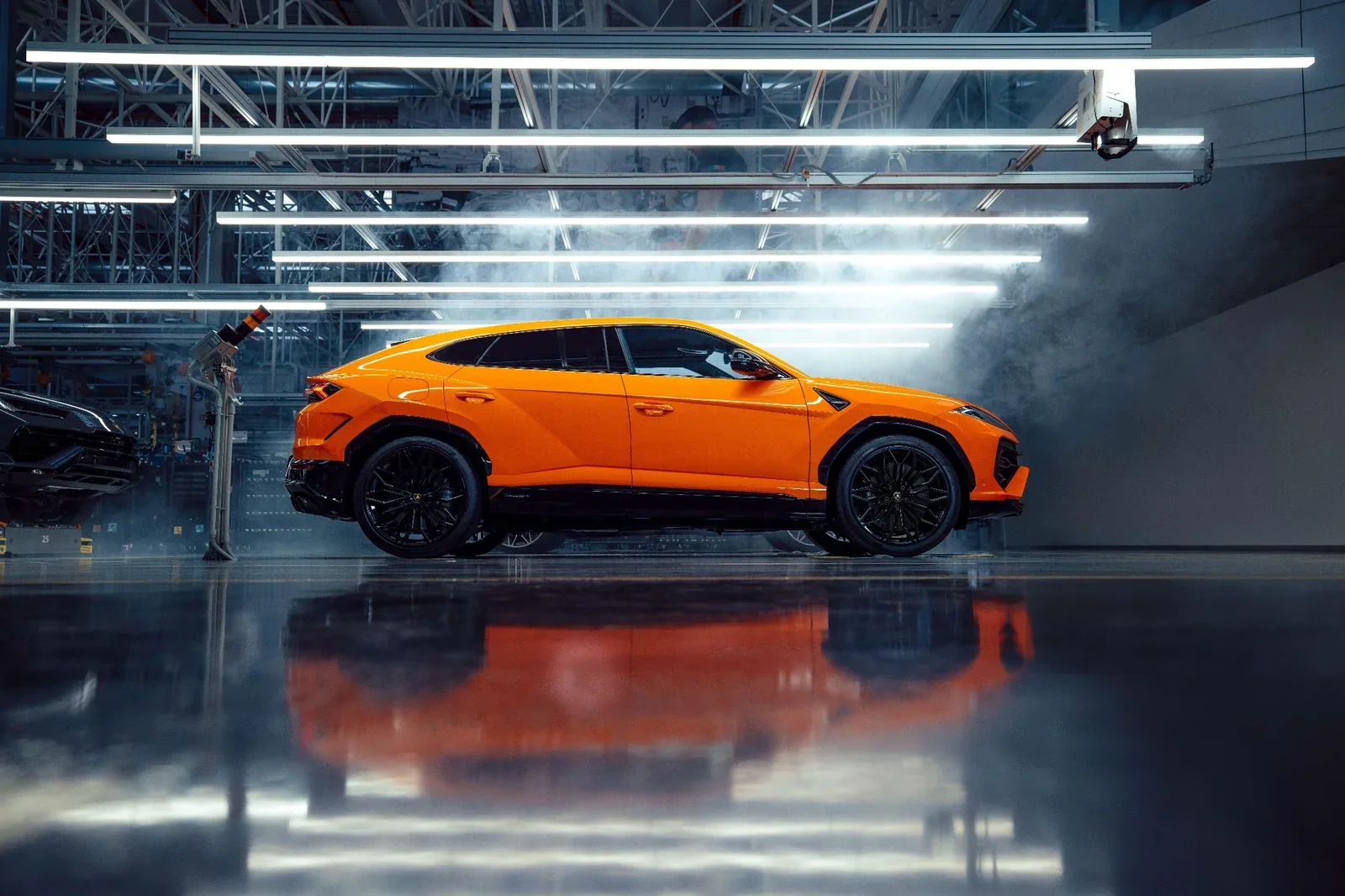 Orange Lamborghini Urus SE side profile at the factory